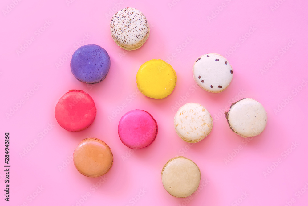French colorful macaroons cakes flat lay. Small sweet biscuits isolated on pink background. Dessert. Happy bithday and valentine’s day creative minimal concept.  Confectionery. Bakery design element.