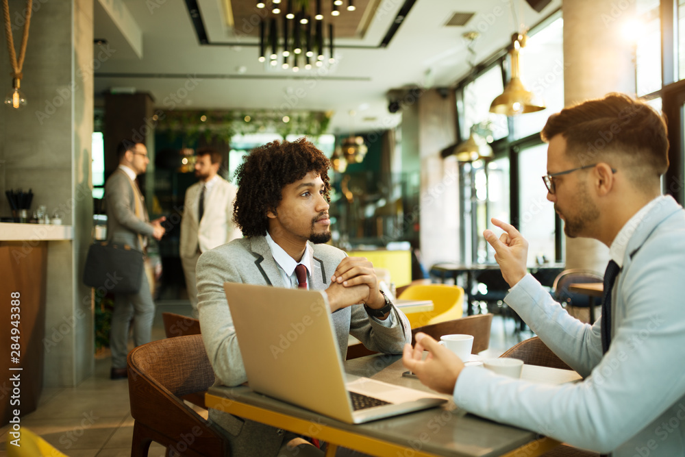 Men are sitting at table in modern cafe. Talk about work Men are sitting at table in modern cafe. Talk about work