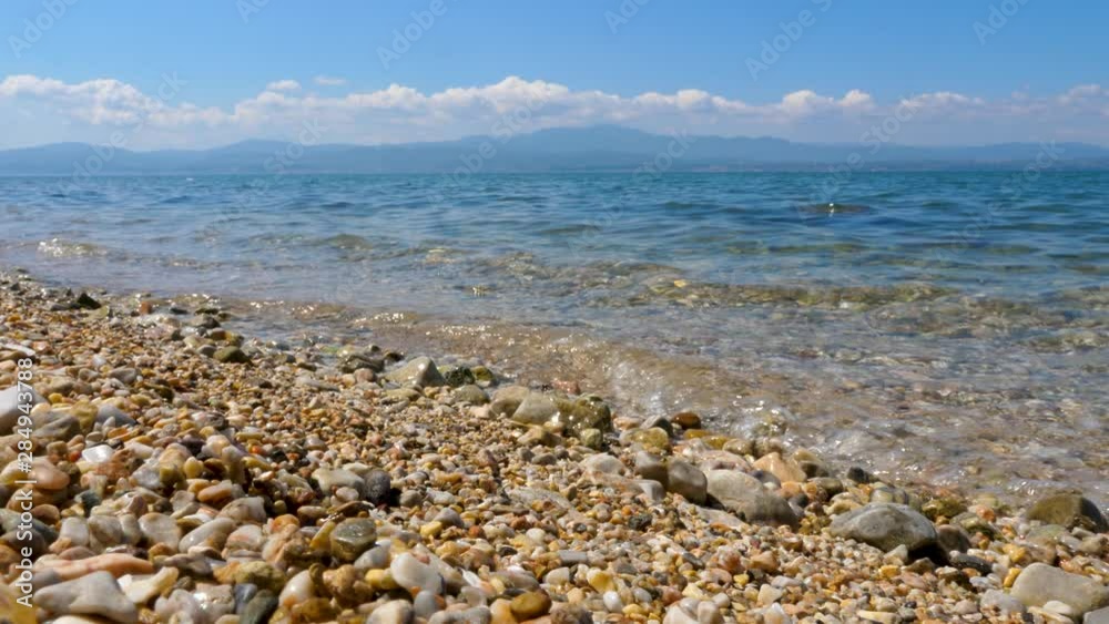 Wonderlust seascape with white clouds and stone seashore. Small waves of the sea with marvelous blue sky. Greek beach with stone, blue water and white clouds. Beach ocean, sea wave at sunny day Wonderlust seascape with white clouds and stone seashore. Small waves of the sea with marvelous blue sky. Greek beach with stone, blue water and white clouds. Beach ocean, sea wave at sunny day
