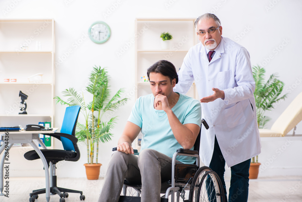 Male patient in wheel-chair visiting old doctor Male patient in wheel-chair visiting old doctor