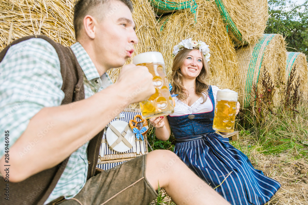 Fototapeta premium Mann und Frau in traditionellen bayerischen trachten kleidung Trinken Bier und lachen