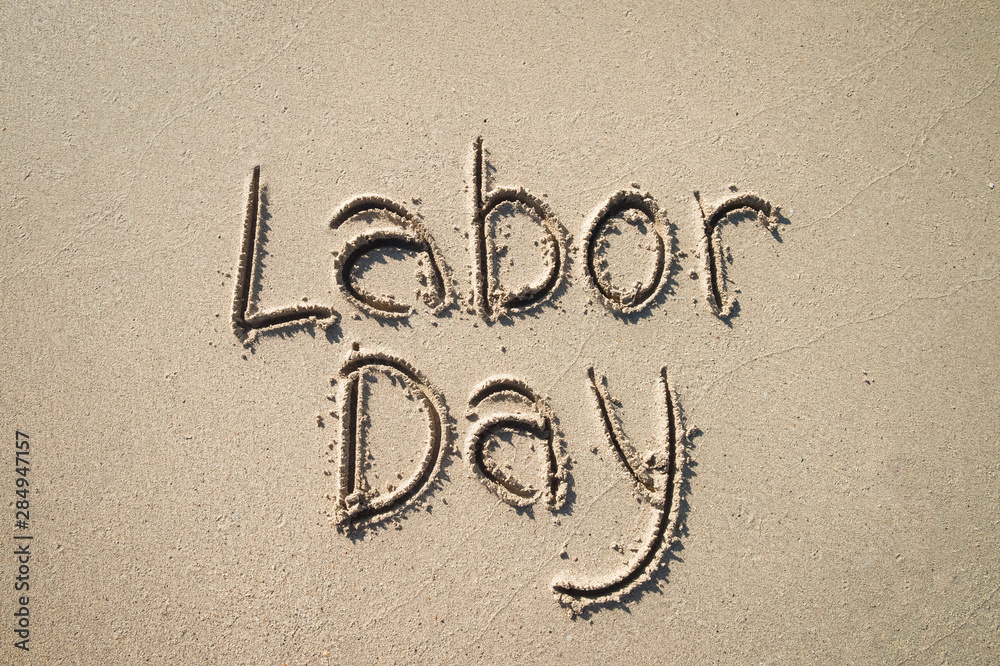 Simple Labor Day message handwritten on the smooth sand of an empty beach