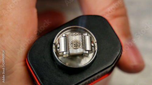 Preparation of mesh coil in the atomizer for vaping. The first heating will cause a low smoke production.
