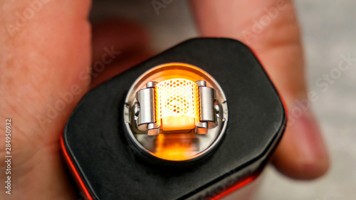 Preparation of mesh coil in the atomizer for vaping - Brightly glowing coil.
