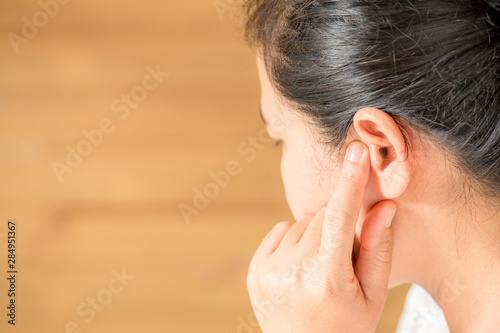 Female having ear pain touching his painful head photo