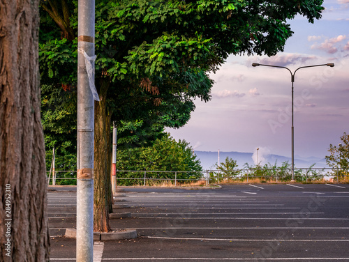 An empty parking lot with trees and a view of the city covered in a foggy morning photo