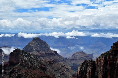 Blue Cloudy Skies Highlight Dark Stony Formations at North Rim of Grand Canyon