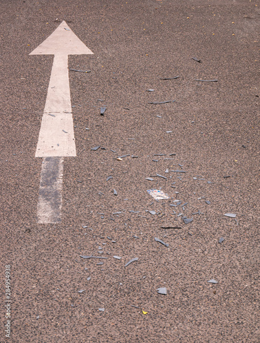 Asphalt road with arrow and cracked plastics from cars