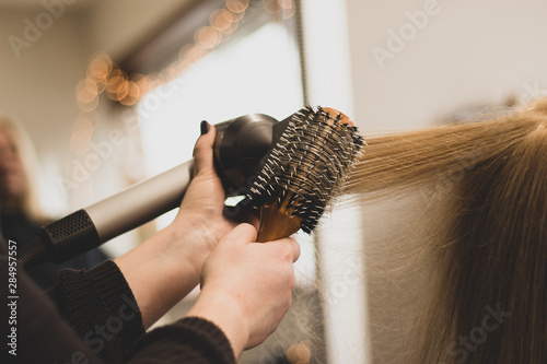 Hair stylist brushing and drying blonde hair in a salon