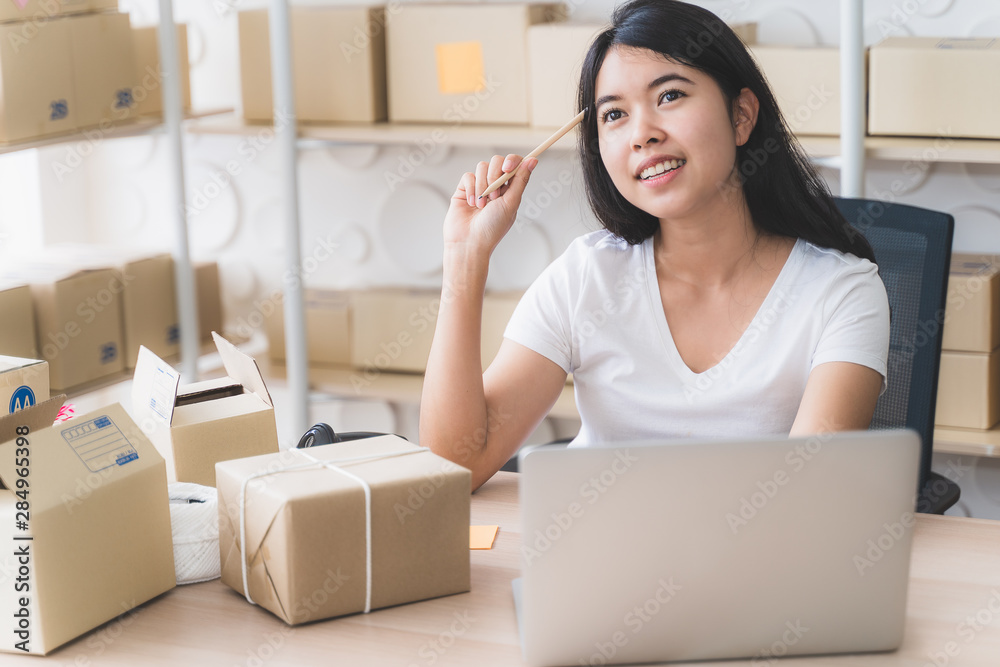 Asian freelance woman working at home and start up small business entrepreneur SME with internet online. Young woman are using laptops to check the number of orders. Asian freelance woman working at home and start up small business entrepreneur SME with internet online. Young woman are using laptops to check the number of orders.