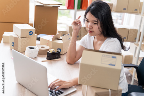 Asian freelance woman working at home and start up small business entrepreneur SME with internet online. Young woman are using laptops to check the number of orders. © amornchaijj