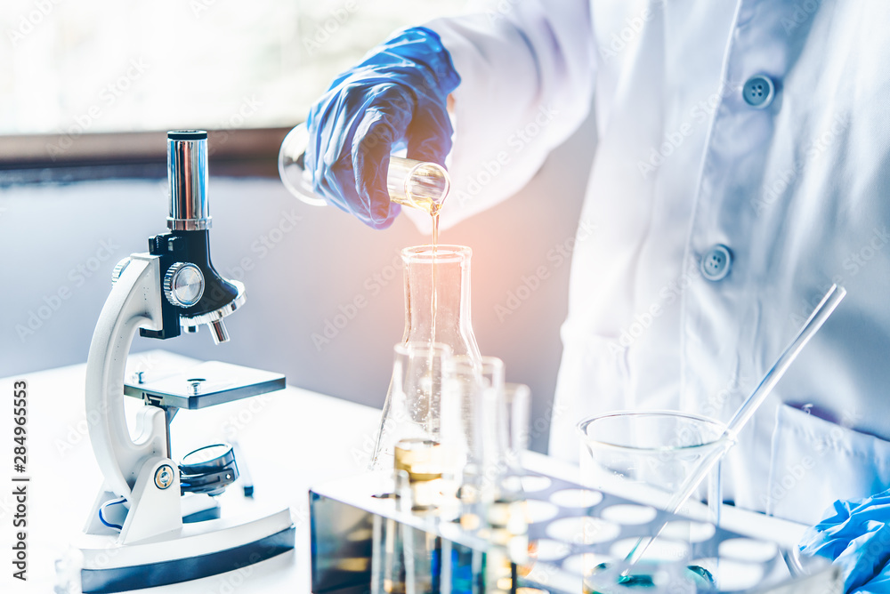 Fototapeta premium Equipment and science experiments oil pouring scientist with test tube yellow making research in laboratory.