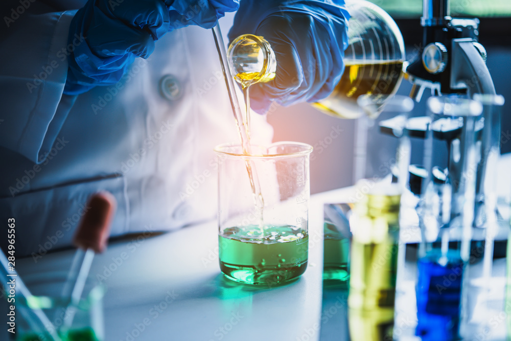 Equipment and science experiments oil pouring scientist with test tube yellow making research in laboratory. Equipment and science experiments oil pouring scientist with test tube yellow making research in laboratory.