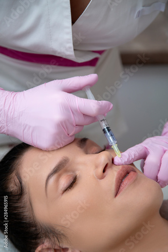 The girl does the procedure for lip augmentation in the cosmetologist’s office