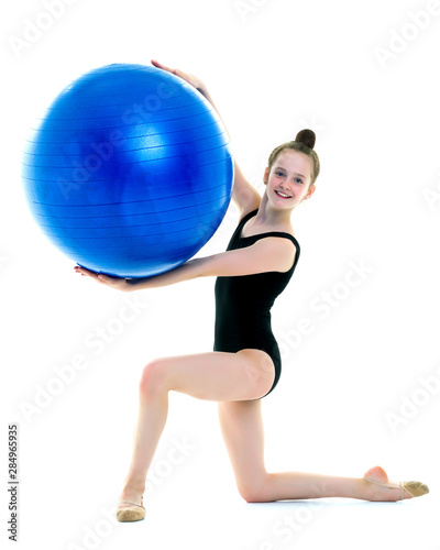little girl doing exercises on a big ball for fitness.