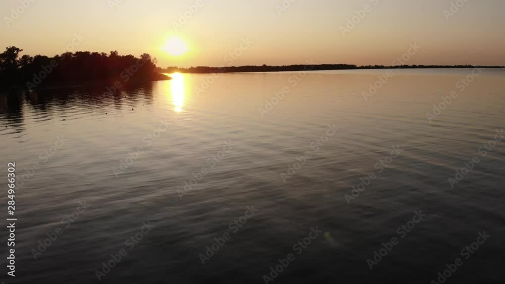 Slow flying drone at sunset over a large area of water with gentle waves and a beach Slow flying drone at sunset over a large area of water with gentle waves and a beach