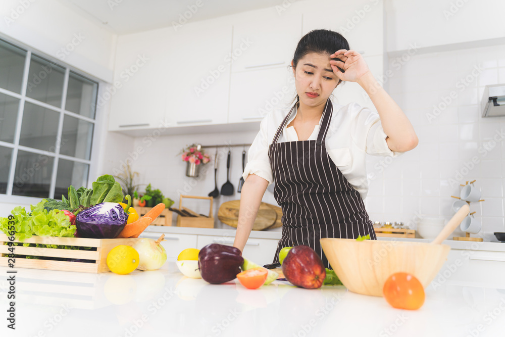 Young woman or housewife is tired of cooking, which consists of a variety of fruits and vegetables for the family.