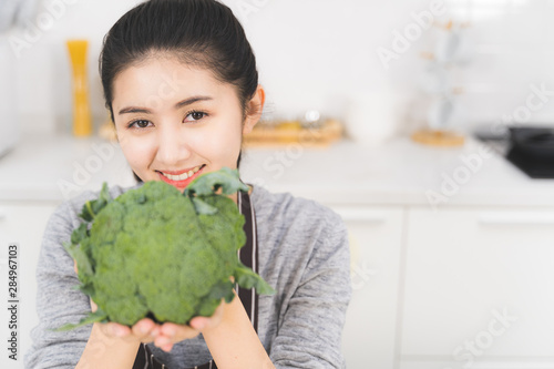 Beautiful asian woman is preparing to cook healthy food which consists of a variety of fruits and vegetables for the family. Portrait of housewife is smiling and holding broccoli.