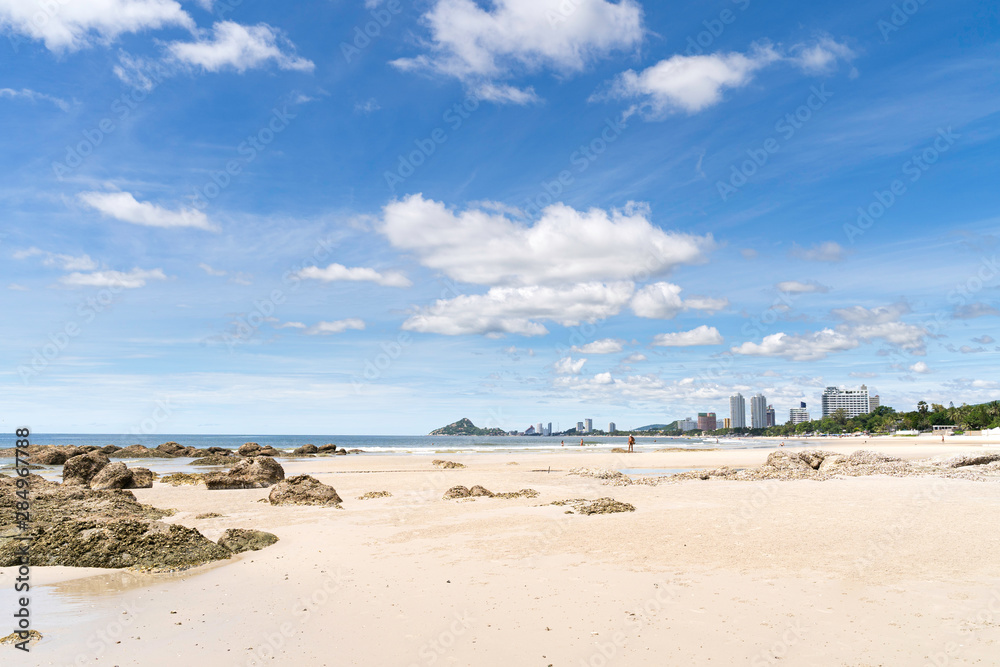 Beautiful beach with rock, blue sky and city background at Hua Hin beach Prachuap Khiri Khan Province, Thailand.