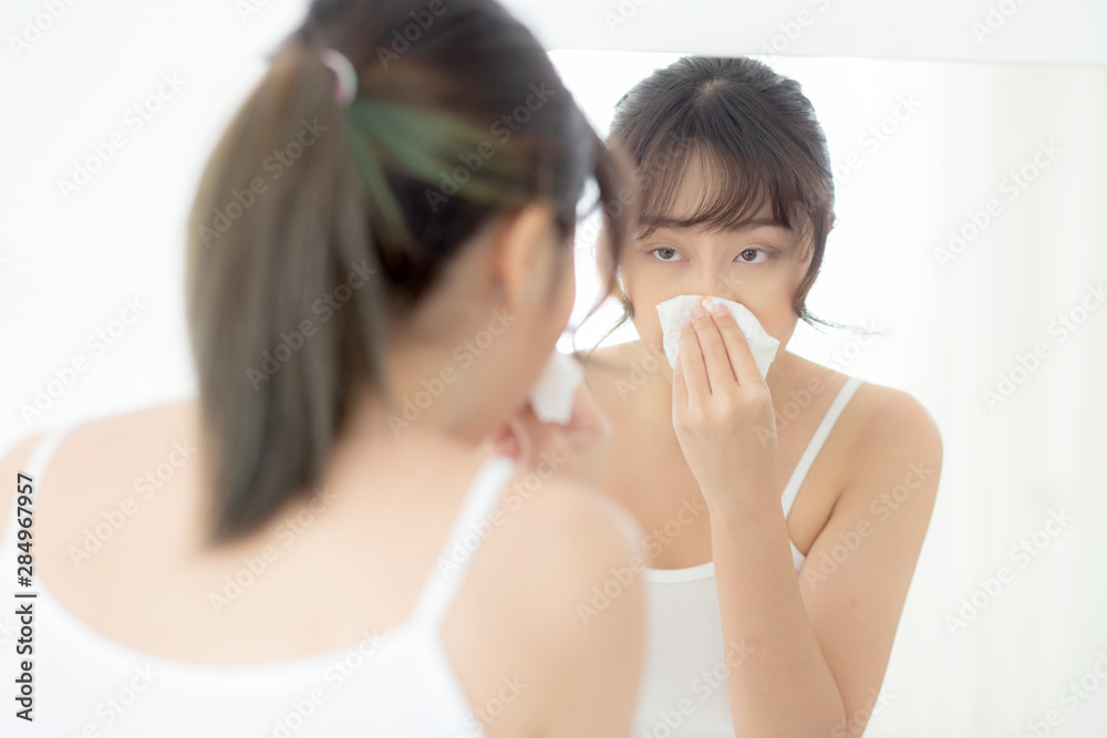 Beautiful portrait asian woman smiling with skin care cosmetic use oil blotting paper on face looking mirror at room, beauty asia girl wipe and cleansing makeup with tissue, clean on facial concept. Beautiful portrait asian woman smiling with skin care cosmetic use oil blotting paper on face looking mirror at room, beauty asia girl wipe and cleansing makeup with tissue, clean on facial concept.