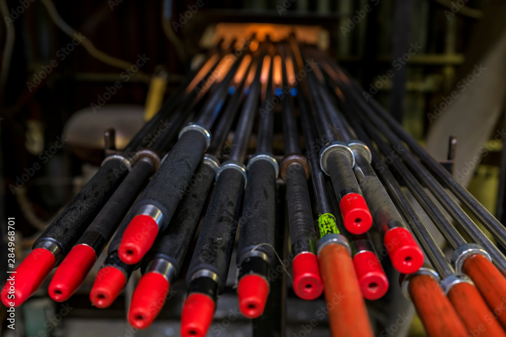 Glass blowing pipes warming up in a traditional furnace at a glass maker's workshop set up for the process
