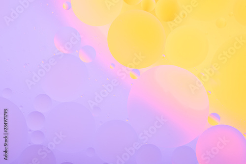 bright oily drops in water with colorful background, close-up 