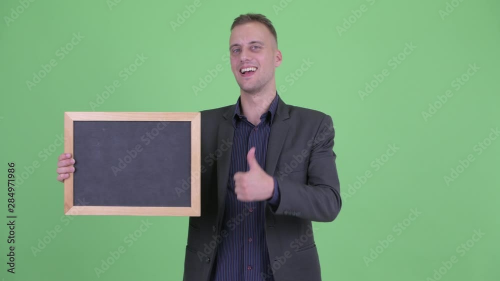Happy handsome businessman in suit holding blackboard giving thumbs up Happy handsome businessman in suit holding blackboard giving thumbs up