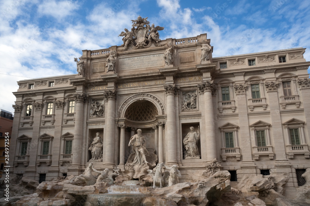 The facade of the Palazzo Poli and part of the Trevi fountain on the Roman Piazza di Trevi against the beautiful sky in Italy.