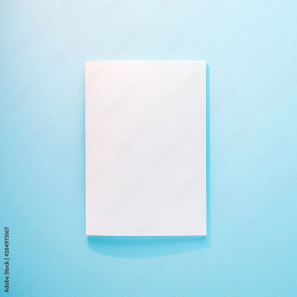 Blank magazine, notebook, brochure, booklet or book with softcover mockup template in the sunlight on blue background Blank magazine, notebook, brochure, booklet or book with softcover mockup template in the sunlight on blue background