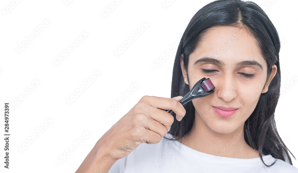 indian teenager girl using derma roller isolated on white background. skin care. Roller ,microneedle, mesotherapy, rejuvenating, beautification indian teenager girl using derma roller isolated on white background. skin care. Roller ,microneedle, mesotherapy, rejuvenating, beautification