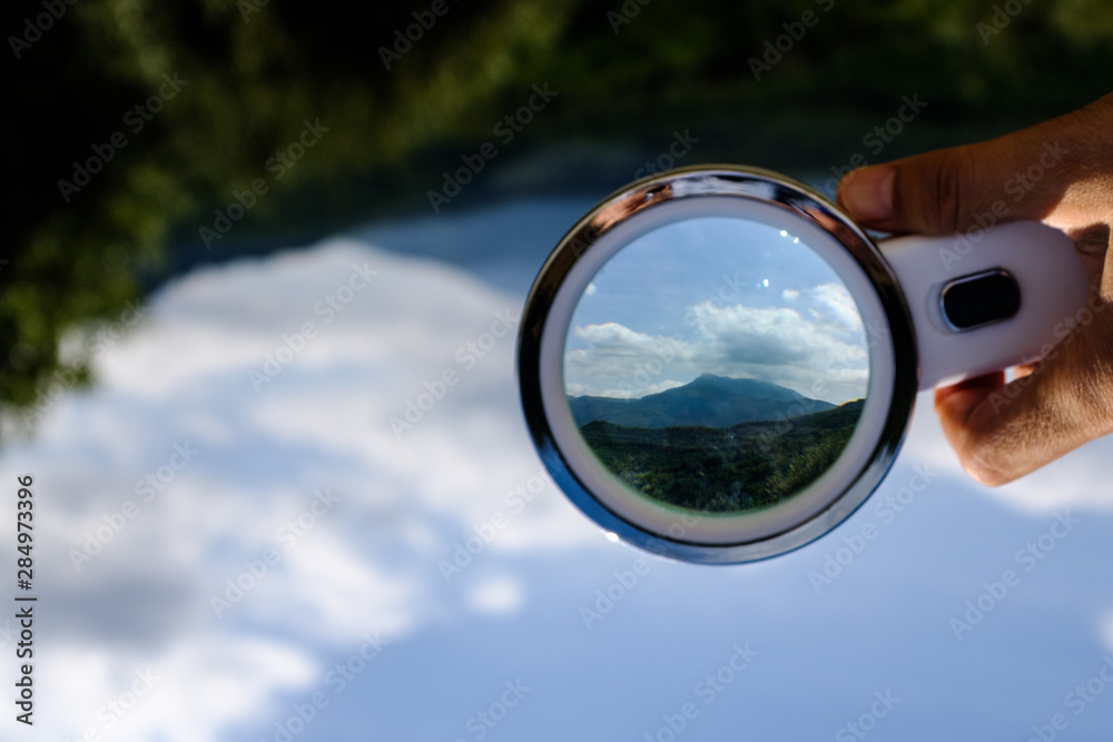 Handheld Loupe optical magnification effects view upside down on a green and blue nature landscape Handheld Loupe optical magnification effects view upside down on a green and blue nature landscape