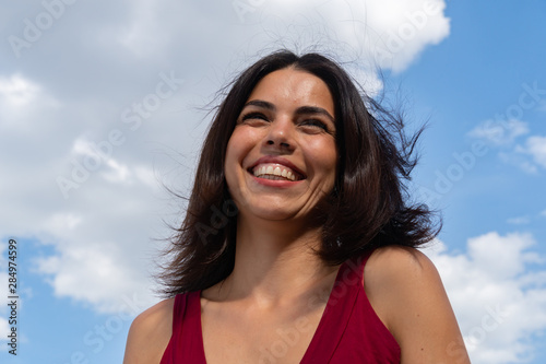 Low angle close-up portrait of a young brunette smiling woman. Low-angle shot