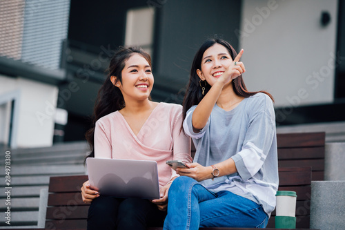 Photography Young long haired Asian woman gesturing with finger up to friend sitting nearby
