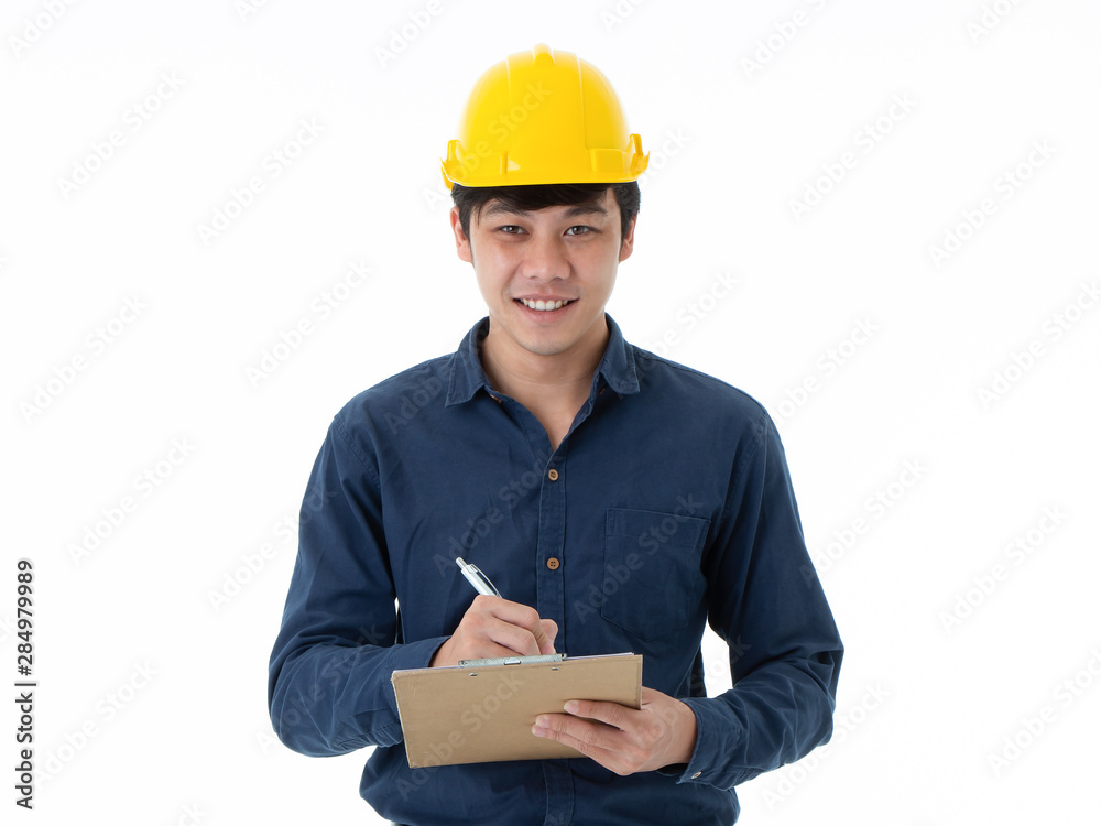 Portrait Of smiling young engineer in yellow helmet hand holding checklist paper clipboard and writing isolated on white background. Portrait Of smiling young engineer in yellow helmet hand holding checklist paper clipboard and writing isolated on white background.