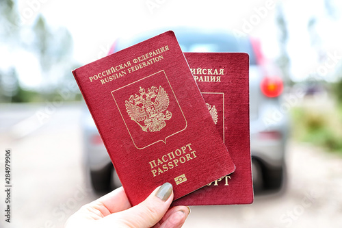 Russian passports in the hand of woman and car background