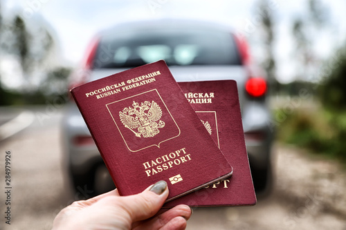 Russian passports in the hand of woman and car background