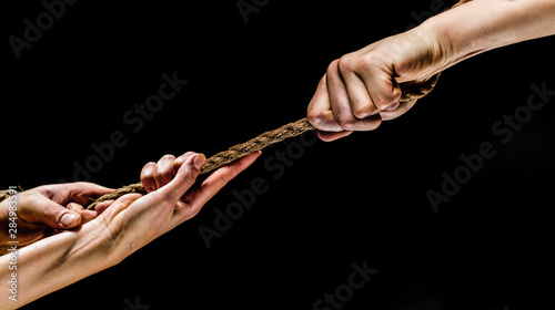 Conflict, tug-of-war, rope. Hand holding a rope, climbing rope, strength and determination concept. Safety. Macro shot isolated over black background.