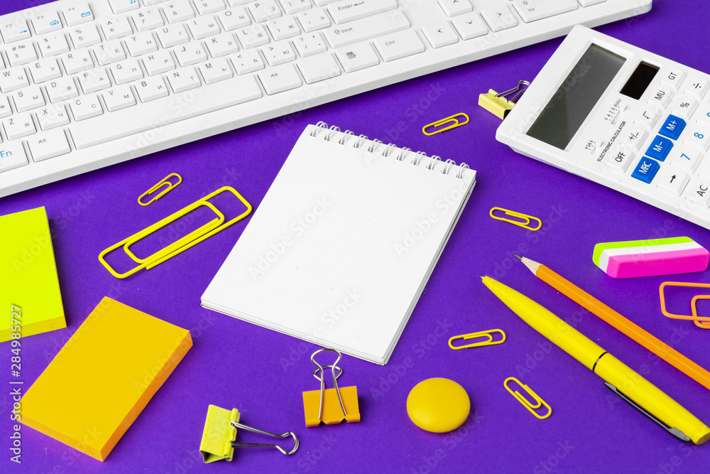 Composition of office lifestyle items on purple background, computer keyboard office supplies on desk in office Composition of office lifestyle items on purple background, computer keyboard office supplies on desk in office