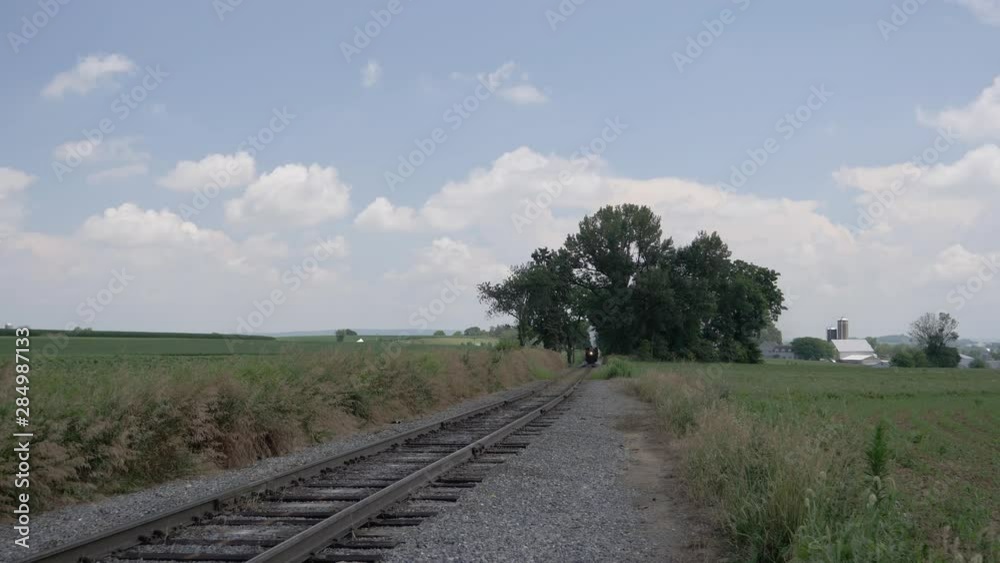 Steam Passenger Train Puffing Black Smoke Along Amish Countryside on a Sunny Summer Day Steam Passenger Train Puffing Black Smoke Along Amish Countryside on a Sunny Summer Day