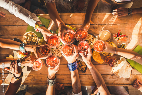 Sticker Top view of group of females people clinking and have un together with red wine and table full of food - friendship and celebration concept - colors and nice background event