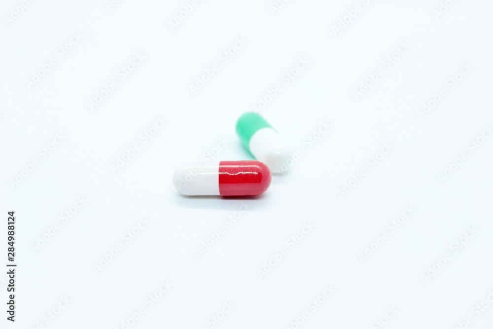 Multi-colored pill capsules are located on a white background Multi-colored pill capsules are located on a white background