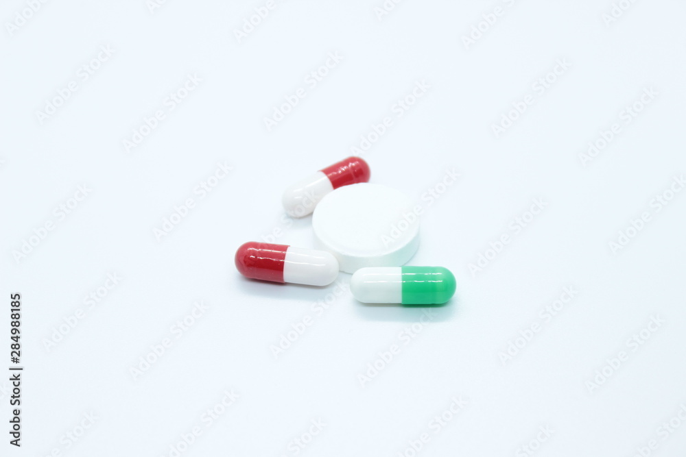 Multi-colored pill capsules are located on a white background Multi-colored pill capsules are located on a white background