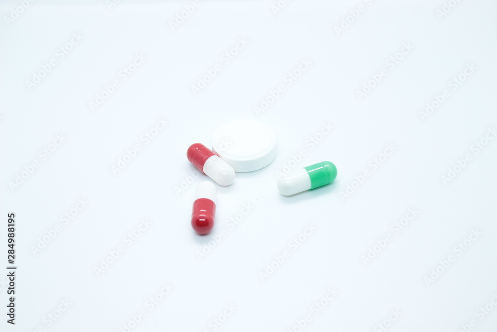 Multi-colored pill capsules are located on a white background