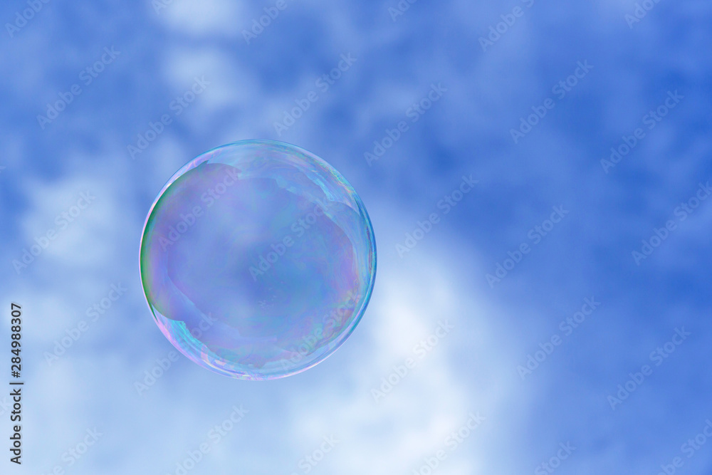 a single bubble blowing in the air against blue sky. Close up a single bubble blowing in the air against blue sky. Close up