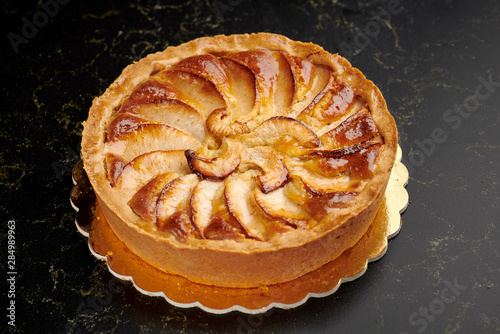 Apple pie on a golden plate on a marble board