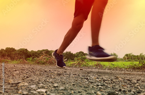 Close-up Legs of Asian young man is jogging on dirt road in the park. Healthy lifestyle.