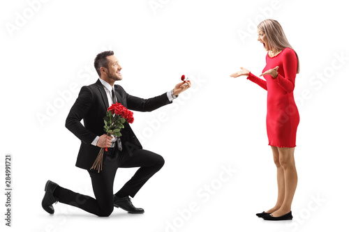 Valokuvatapetti Young man kneeling with roses and an engagement ring and proposing to a surprise