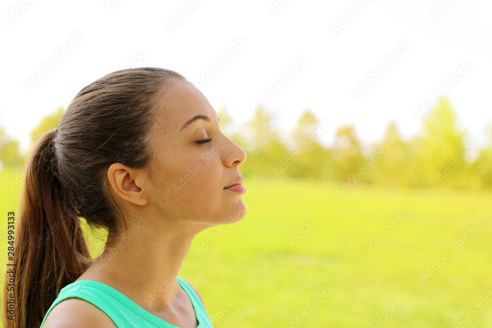 Side view portrait of woman relaxing breathing fresh air deeply in the park. Copy space. Side view portrait of woman relaxing breathing fresh air deeply in the park. Copy space.