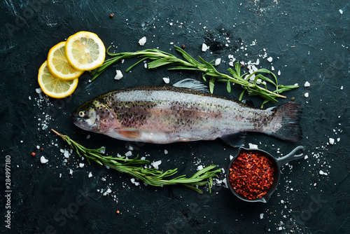 Raw fish trout with vegetables on a black stone background. Top view. Free space for your text. photo