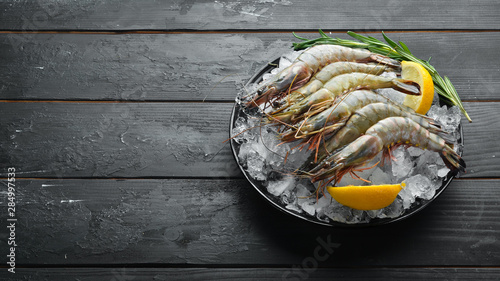 black tiger prawns with lemon on ice. Seafood. Top view. On a black background. Free copy space. photo